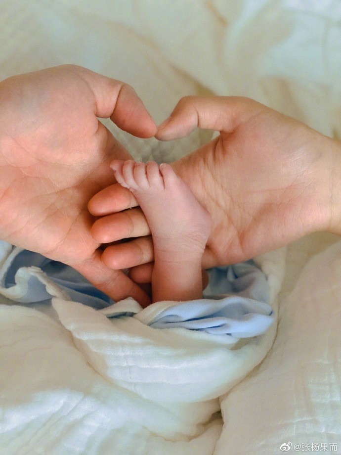 出了一家三口的合照,画面中的她和老公百克力用手托着小宝宝的脚丫子