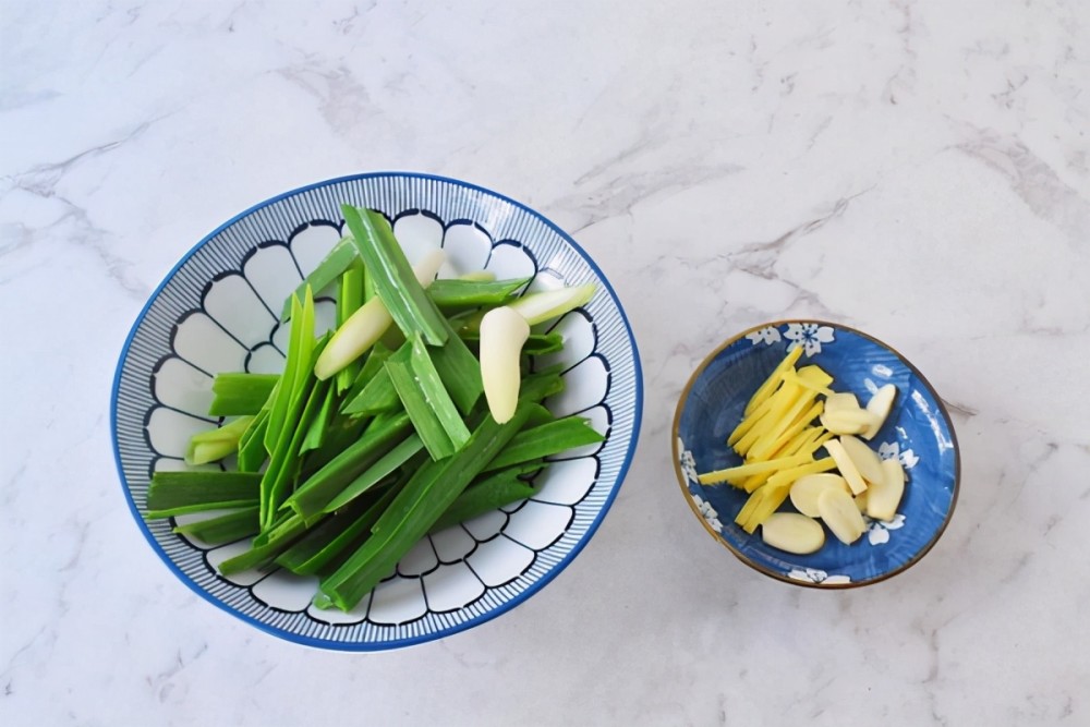 2,大葱切成葱段,装在碗中,放在一旁备用,扒好的蒜也切成蒜末,姜切成姜
