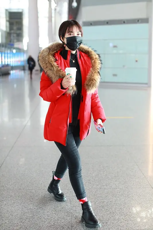 卢靖姗身穿红色毛领羽绒服,搭配的黑色毛衣和黑色紧身裤,经典的黑红