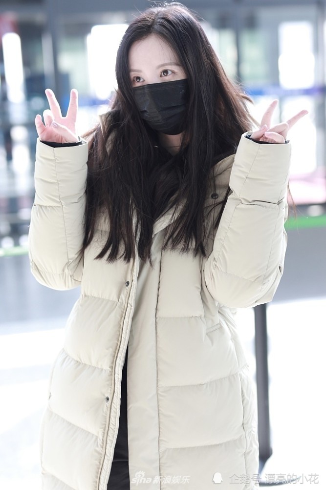 张萌举零食投喂粉丝双手比v穿白色羽绒服气质温柔
