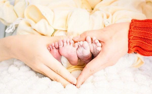 并通过一对女儿双脚以及夫妻俩双手比心出镜的方式,晒出一家四口的