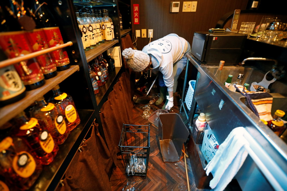 2月14日,在日本福岛县磐城,一名酒吧老板清理因地震碎掉的酒瓶.