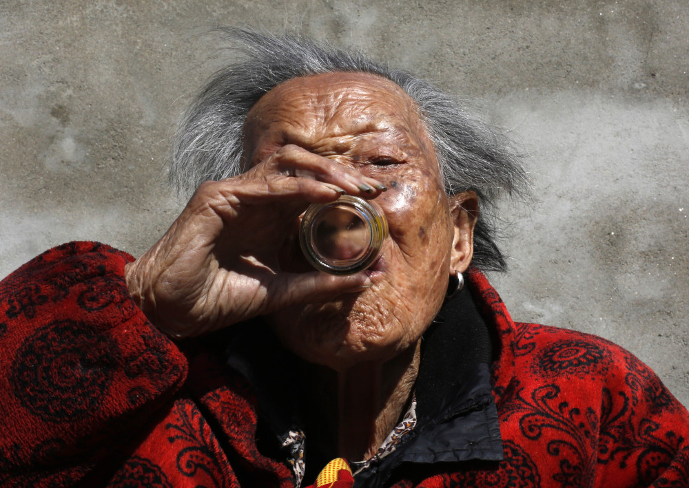 白酒在前,老人端起酒杯,动作麻利一下倒进口中.