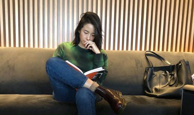 林嘉欣穿着一件深绿色的毛衣,脚上穿着一条蓝色的牛仔裤和一双紫红色