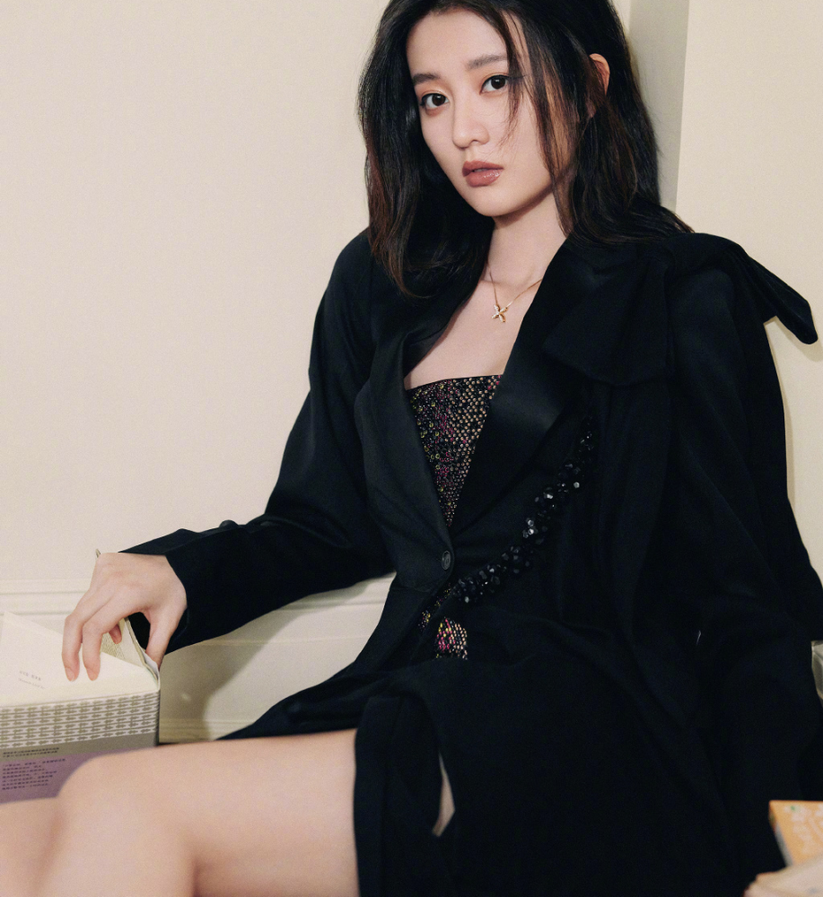 照片中,乔欣穿着一件黑色吊带装,坐地毯上靠在床边,下面还穿着性感的