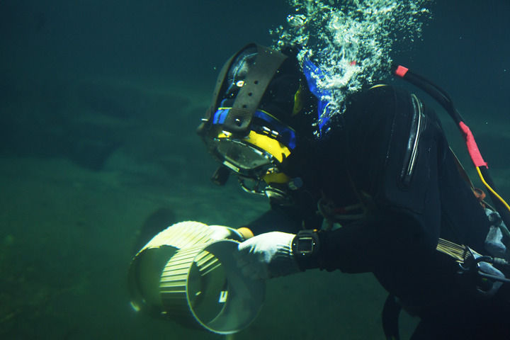 3月15日,潜水员在对取下的灯罩进行检查.