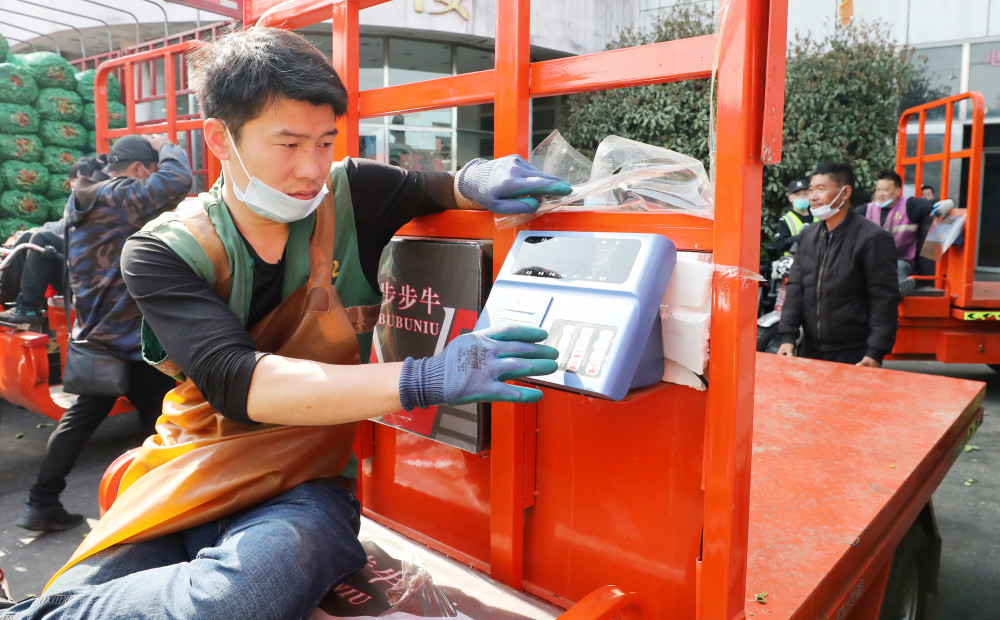 3月25日,在上海江桥批发市场内,一名短驳车司机在操作安装在车辆上的