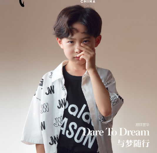 易烊昱华身穿白色字母衬衫内搭黑色t恤和短裤,梳着和哥哥千玺一样的