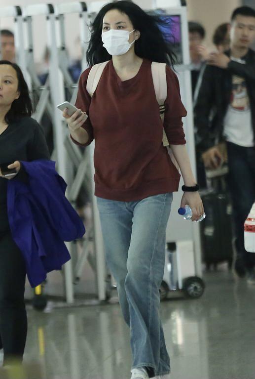 王菲现身机场她身穿一件暗红色卫衣搭配直筒牛仔裤,王菲对于基础款