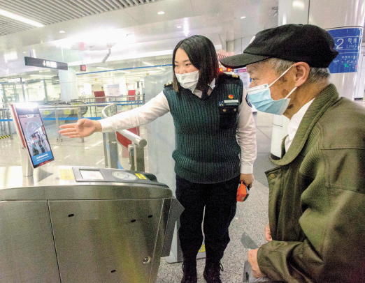 东风广场地铁站入口,地铁工作人员指导老年人使用刷脸设备进站