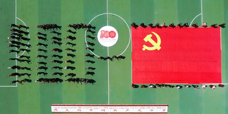 在庄严的国歌声中,身着盛装的干部群众们挥舞着党旗,在操场中用人形摆