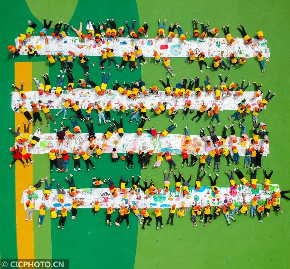 园的小朋友在百米长卷上作画,将自己心中的春天通过五彩画笔展现出来