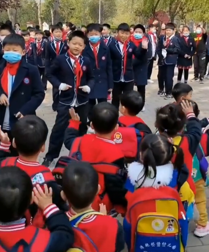 視頻中,小學生春遊偶遇排排走的幼兒園小朋友,雙方紛紛招手示意,一位