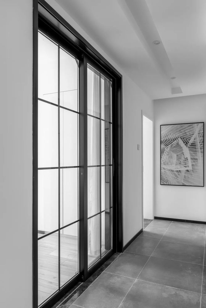 基础,装上黑色玻璃推拉门与贴脚线,墙面挂一幅灰色调的线性几何图案