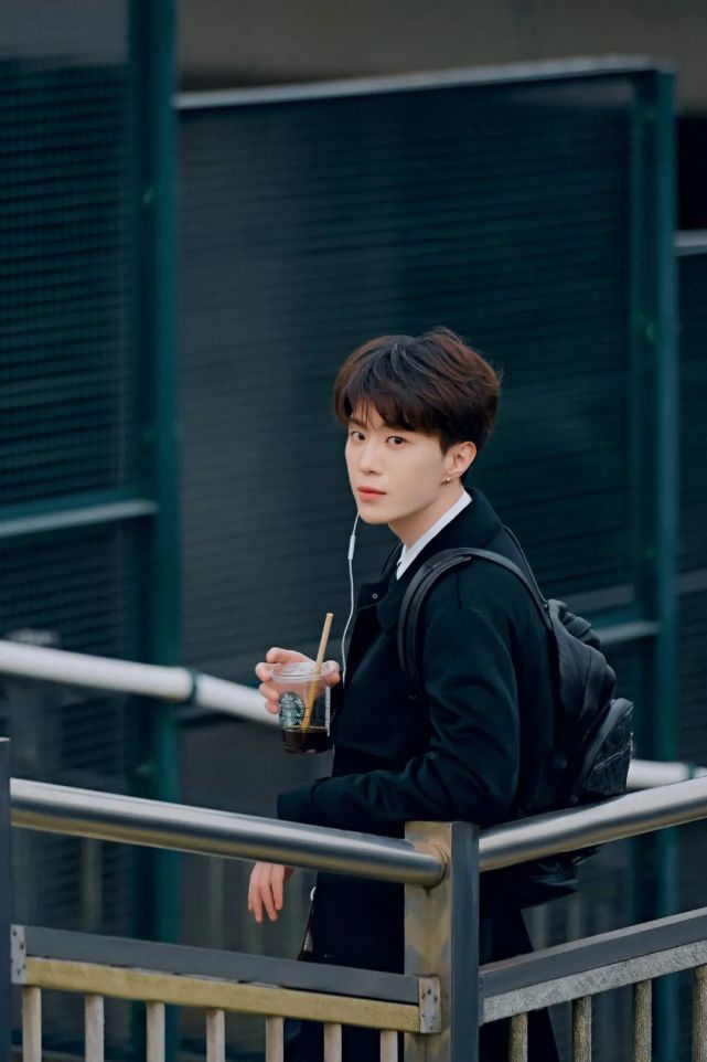 行走在充满春日氛围的街道上,照片中他背着双肩包,单耳挂着耳机