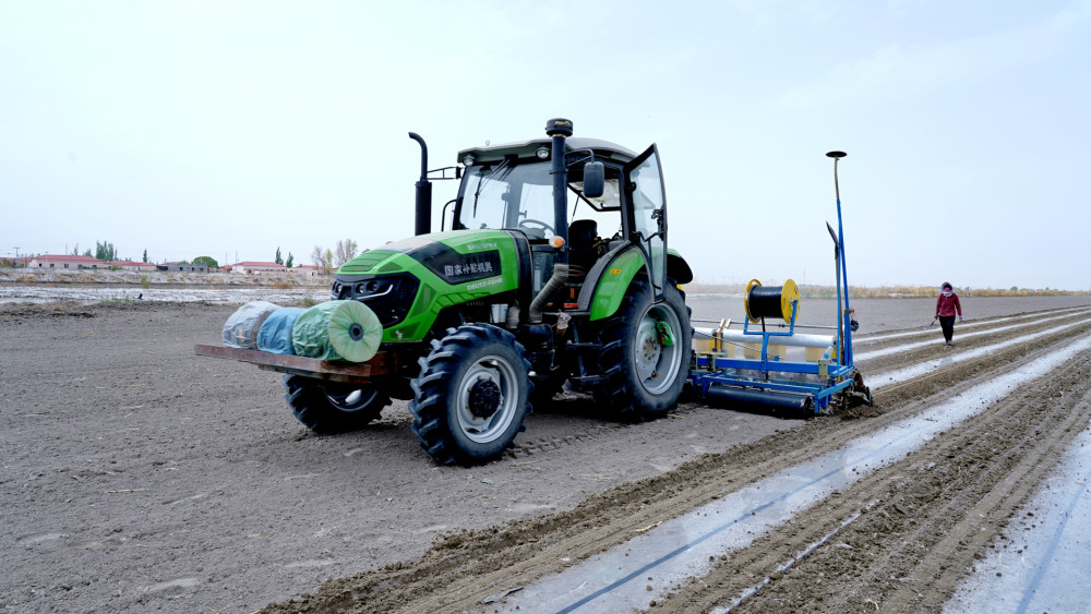 伴随着隆隆的农机发动声,一台棉花播种机正在地里来回穿梭播种,3名