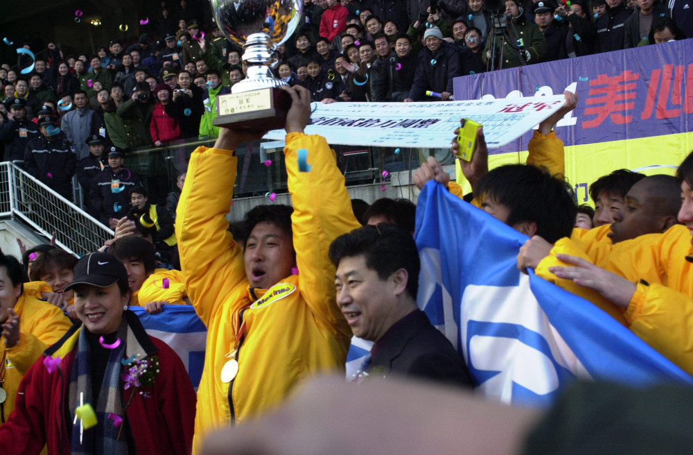 年12月30日,大连队队员张恩华(中)代表球队举起2001年足协杯冠军奖杯