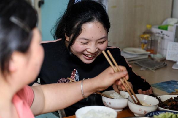 5月8日,母亲侯汝彩(后)在同学的帮助下将女儿马小婷(中)的轮椅搬过铁