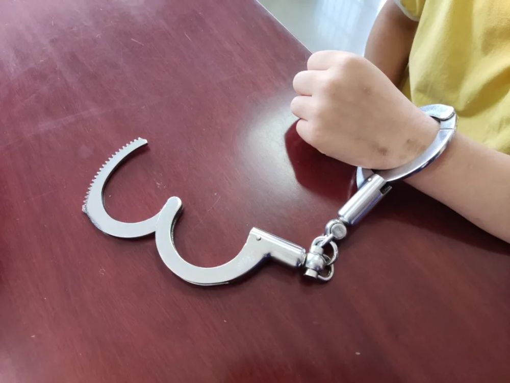 其中,小男孩的左手腕上戴着一副手铐.