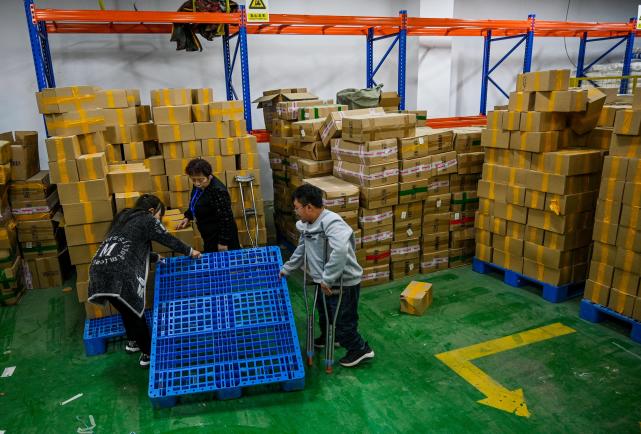 5月12日,在公司仓库里,刘凯(右)和残障同事一起干活.