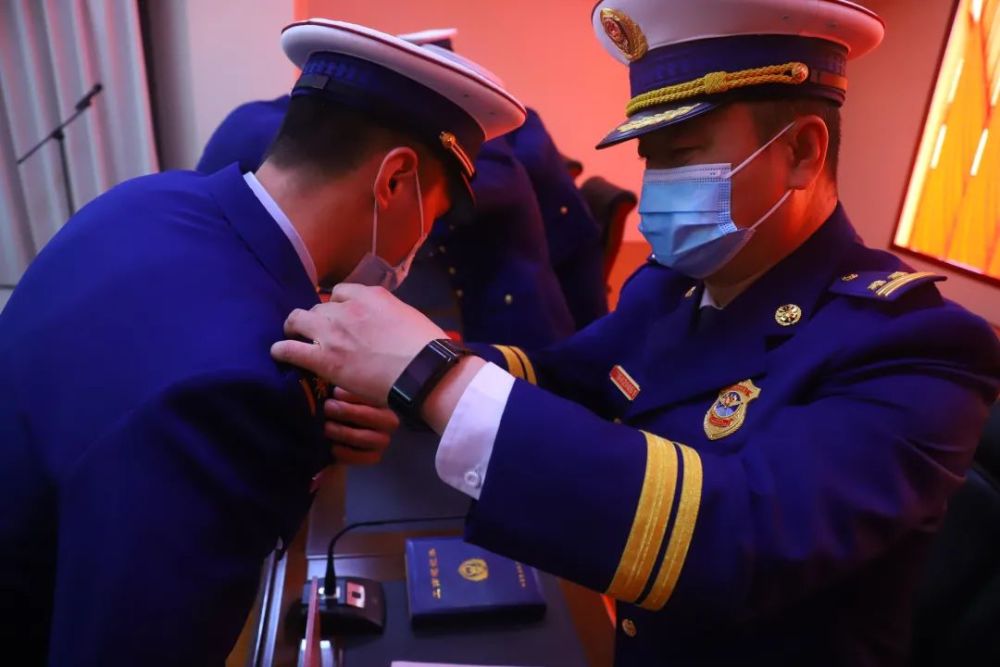 消防救援衔消防员代表颁发命令状,佩戴消防救援衔标志服饰,亲切握手