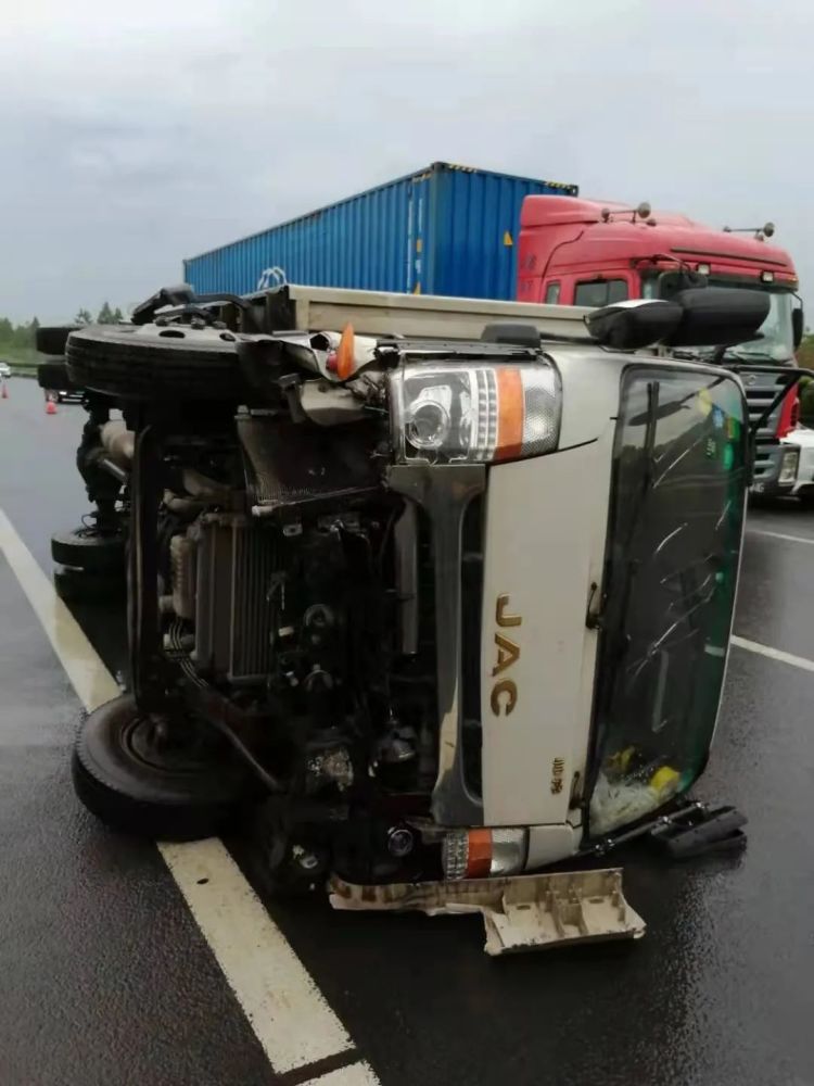 車頭受損嚴重,貨車旁邊的邊護欄被撞得嚴重變了形,護欄外站著一男一女