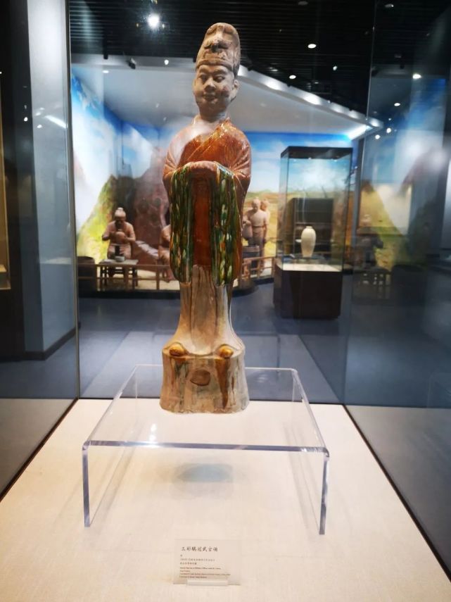 头戴鹖冠,深目高鼻,身穿交领宽袖长衣,双手相握,置于胸前,神情庄严