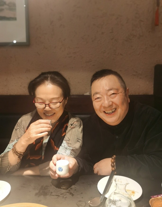 合照中夫妻二人坐在餐桌前,董浩举着茶杯看着镜头笑得很是开心,妻子