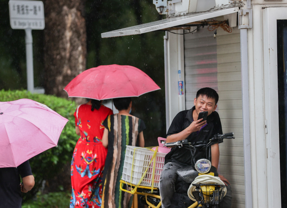 在屋檐下躲雨撑伞冲过积水头戴塑料袋在雨中前行的老人在雨中撑起大