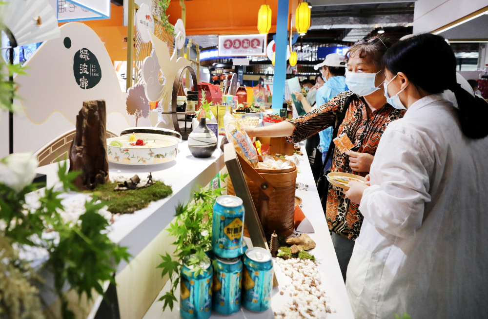 5月29日,参观者在一家豫园老字号饭店展台前挑选商品.