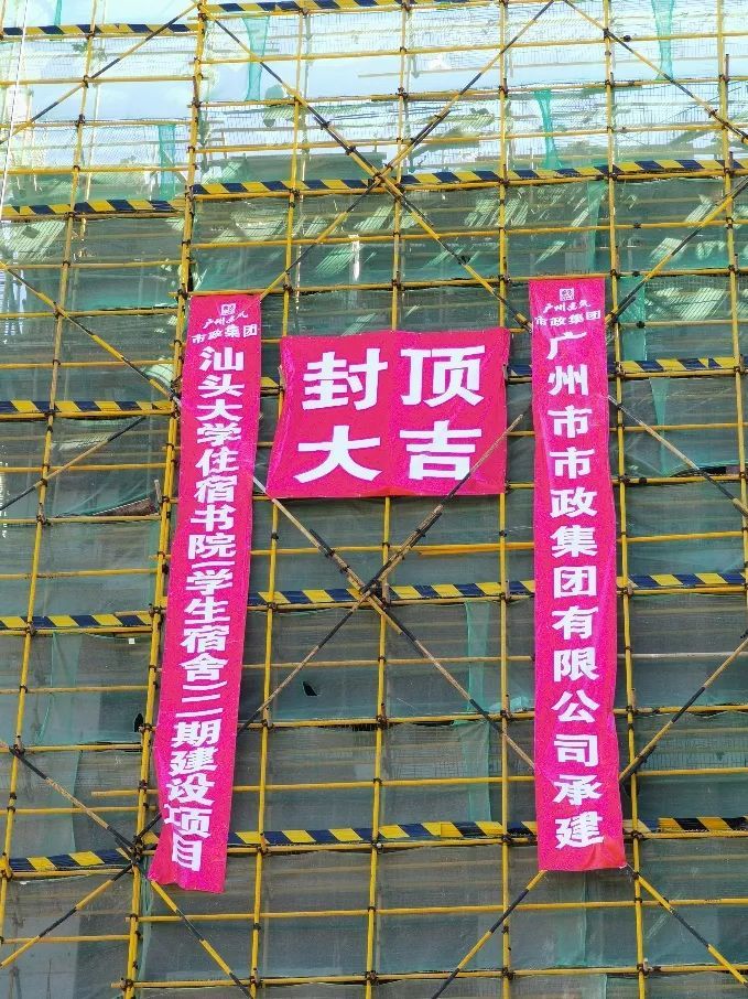 热闹非凡,耸立的大楼主体在"封顶大吉"的红色祝福标语下装点得格外