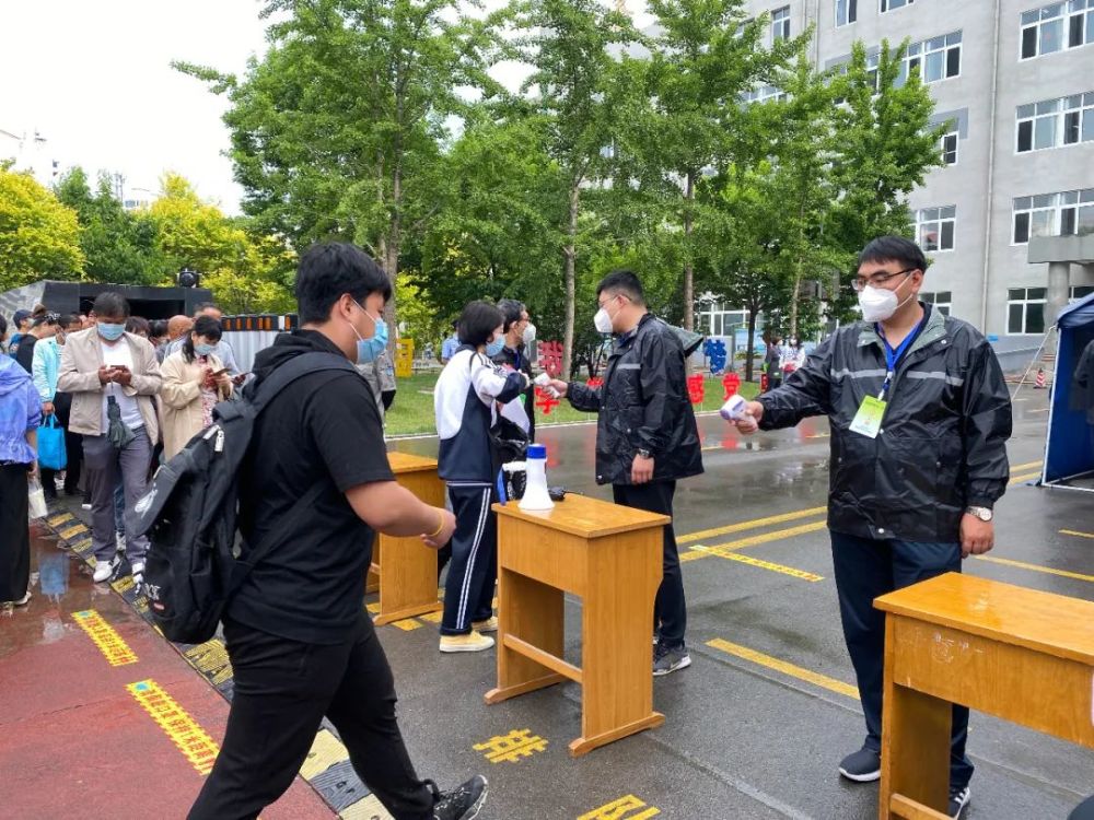 秦皇岛市第三中学考点门前,工作人员为进入考场的考生测量体温