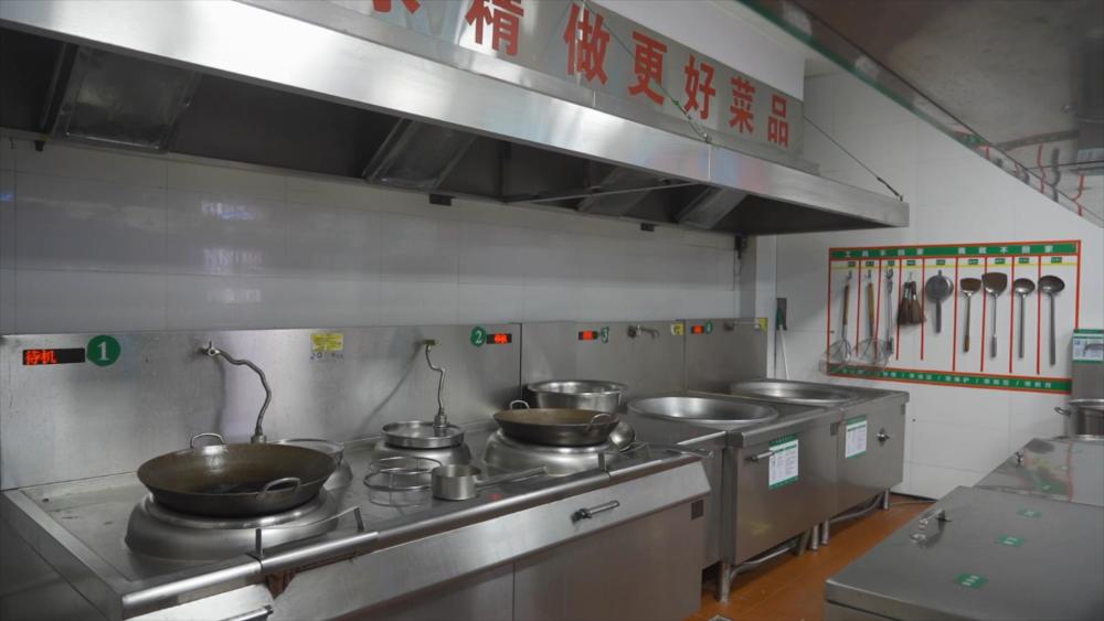 在赣榆区实验中学的食堂厨房内,5台电磁灶整齐排列,电饼铛,电蒸锅,电