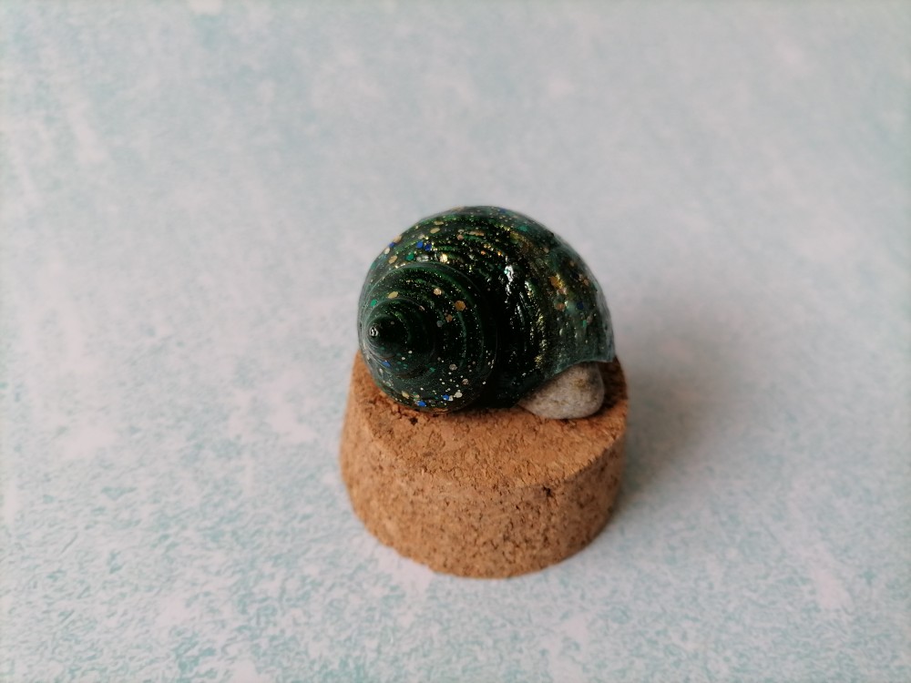 把海螺粘在底座上.因为这个海螺有点不稳,所以放块石头支撑一下.