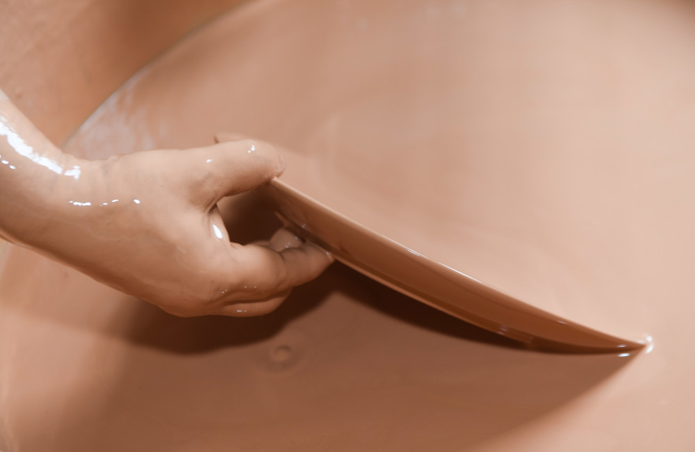 6月17日,中国陶瓷艺术大师孙迈华在车间内给一件陶制品上釉.