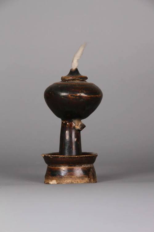 打个孔,孔中嵌进一个用铁皮卷成的小筒 , 捻一束棉线条穿入孔中作灯芯