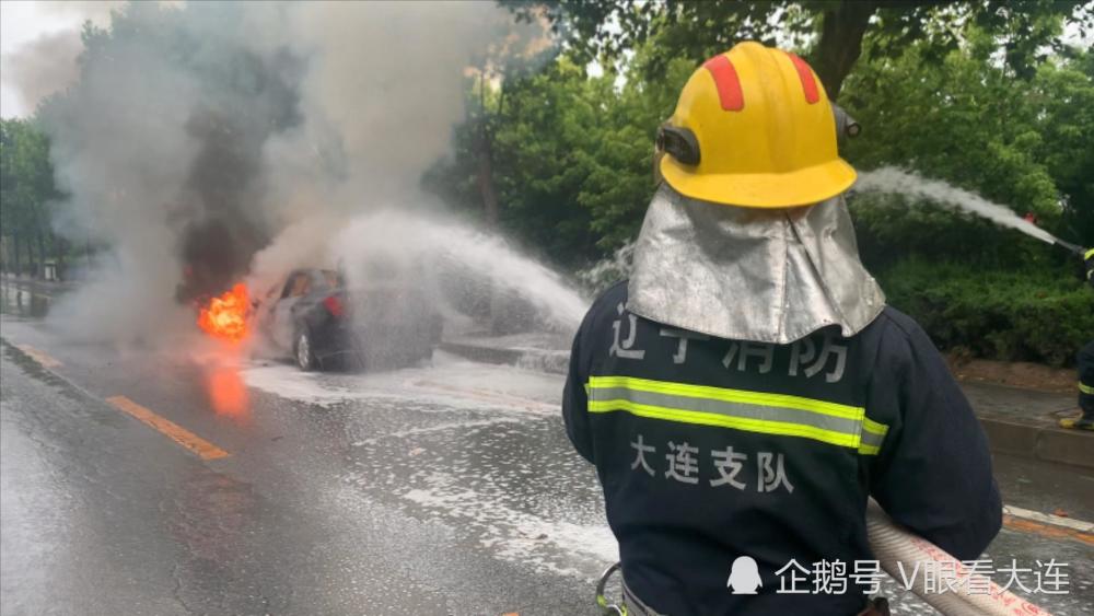 遼寧大連西北路上一轎車雨中突起大火消防員緊急撲救