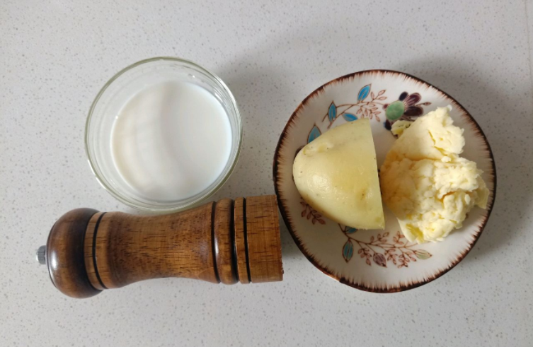 2,烤碗里面先倒入适量的牛奶,然后再将蒸熟了的土豆下进去.