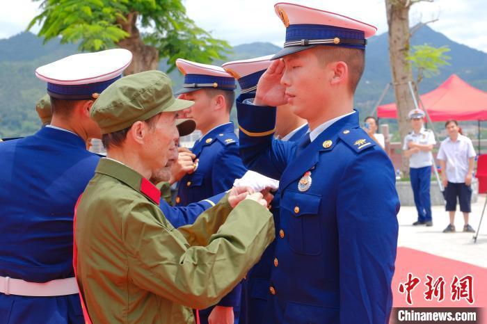 英雄老兵在三河坝战役纪念园为新党员代表佩戴党徽. 林启帆 摄