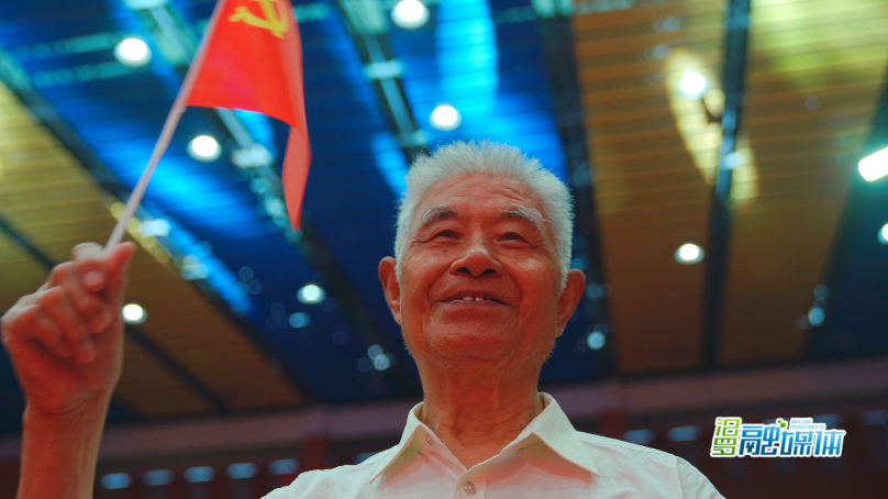 胡志忠老人挥动手中党旗 优秀老党员 甘征文