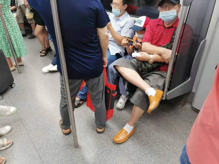 高温天上海地铁乘客呈骤增之势拥挤车厢众多人翘二郎腿走道呈s形酷暑
