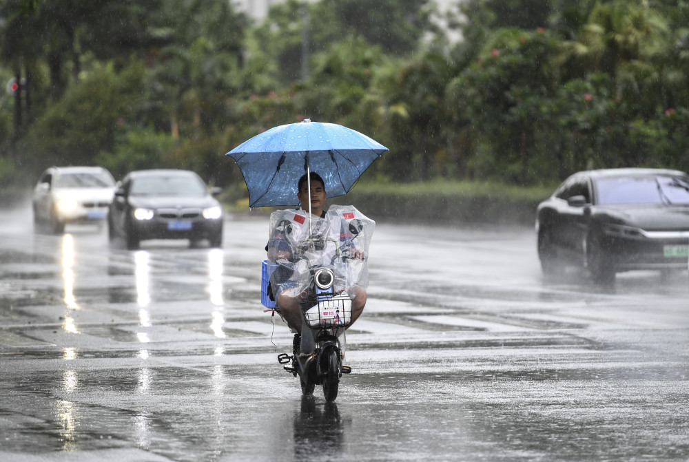 7月19日,居民骑着电动车在雨中前行新华社记者 毛思倩 摄