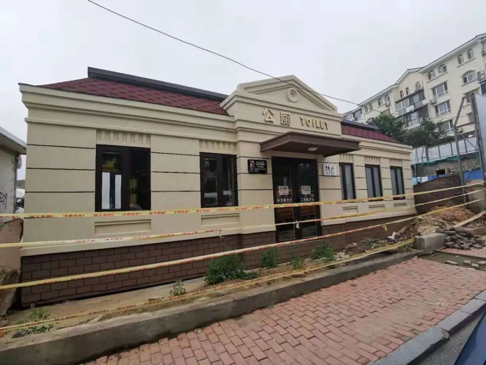 远远看去欧式建筑的公厕,红色坡屋顶,黄色的墙体,褐色的门窗,里面的