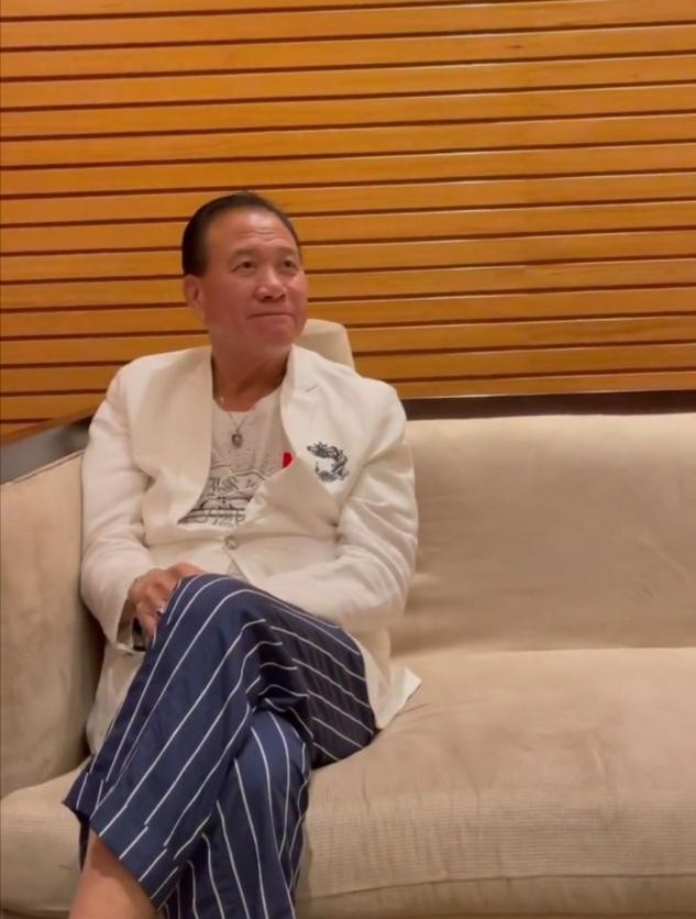 照片中,万梓良身穿白色西装和休闲长裤,脚上的黑红波点长袜格外亮眼