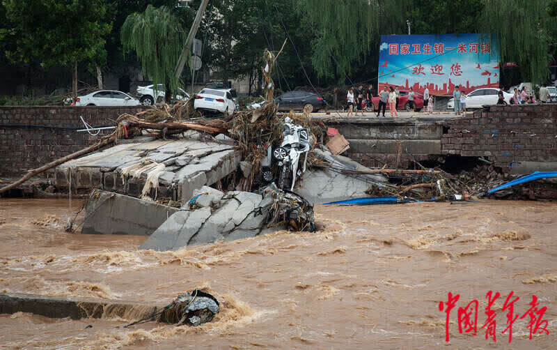 7月22日,河南省巩义市米河镇,洪水中损毁的车辆等堆积在路上