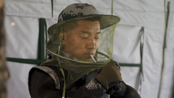 0m戴着防蚊帽,用吸管喝水,这是官兵们总结出的经验,因为一摘防蚊帽