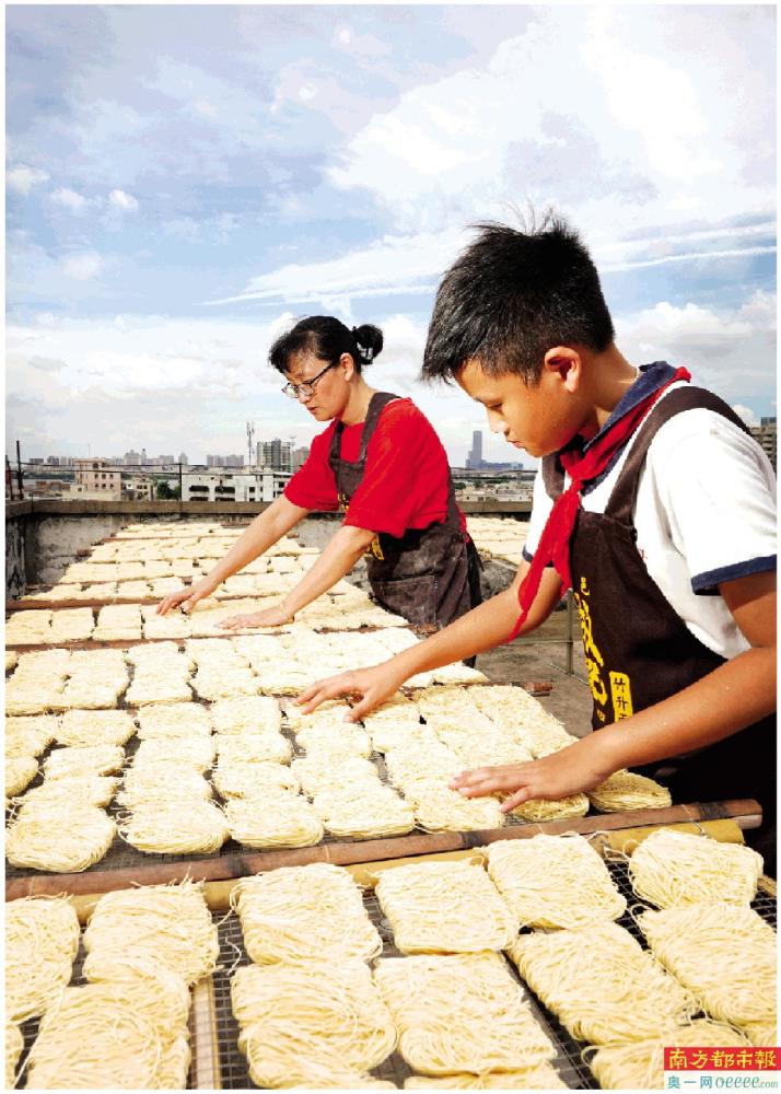 用竹竿擀压面皮后,陈丽娟将面皮放进压面机压成薄片.