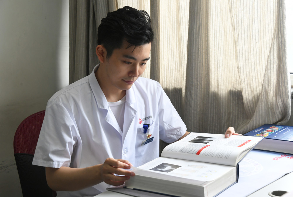 在北京市海淀医院住院楼骨科医生办公室,马元翻阅医学书籍(8月12日摄)