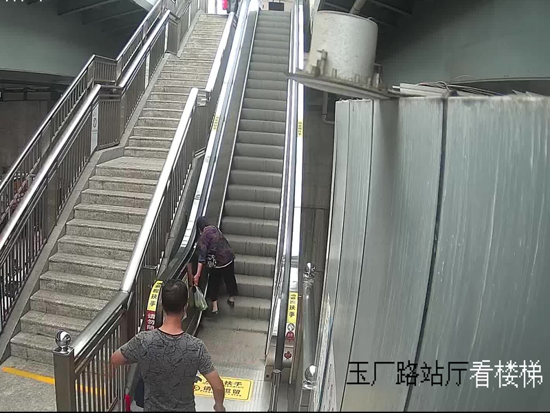 一位双手提菜的老人进站后踏上了手扶电梯,上行一段后,老人突然踩空