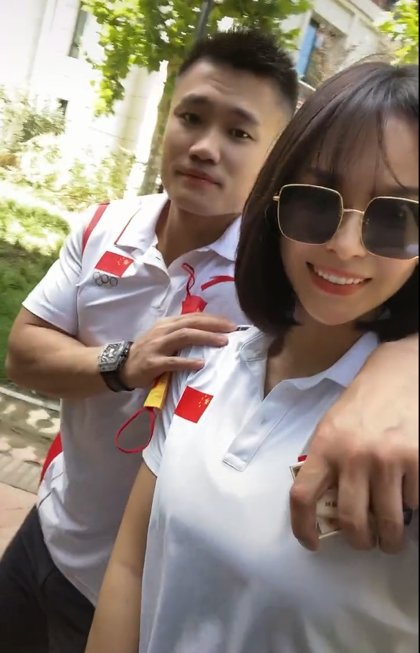 吕小军搭在妻子的肩上,手里攥着一盒烟,而左手戴了一款名表.